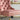 Pink upholstered chair with gold nailhead trim in a room setting.